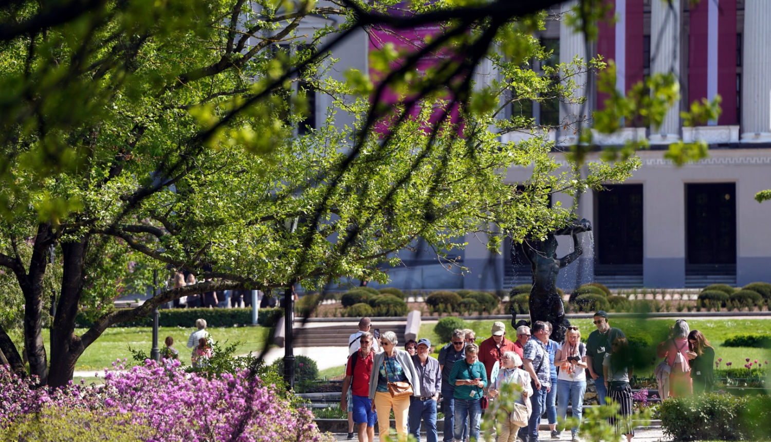 Cilvēki pastaigājas operas skvērā