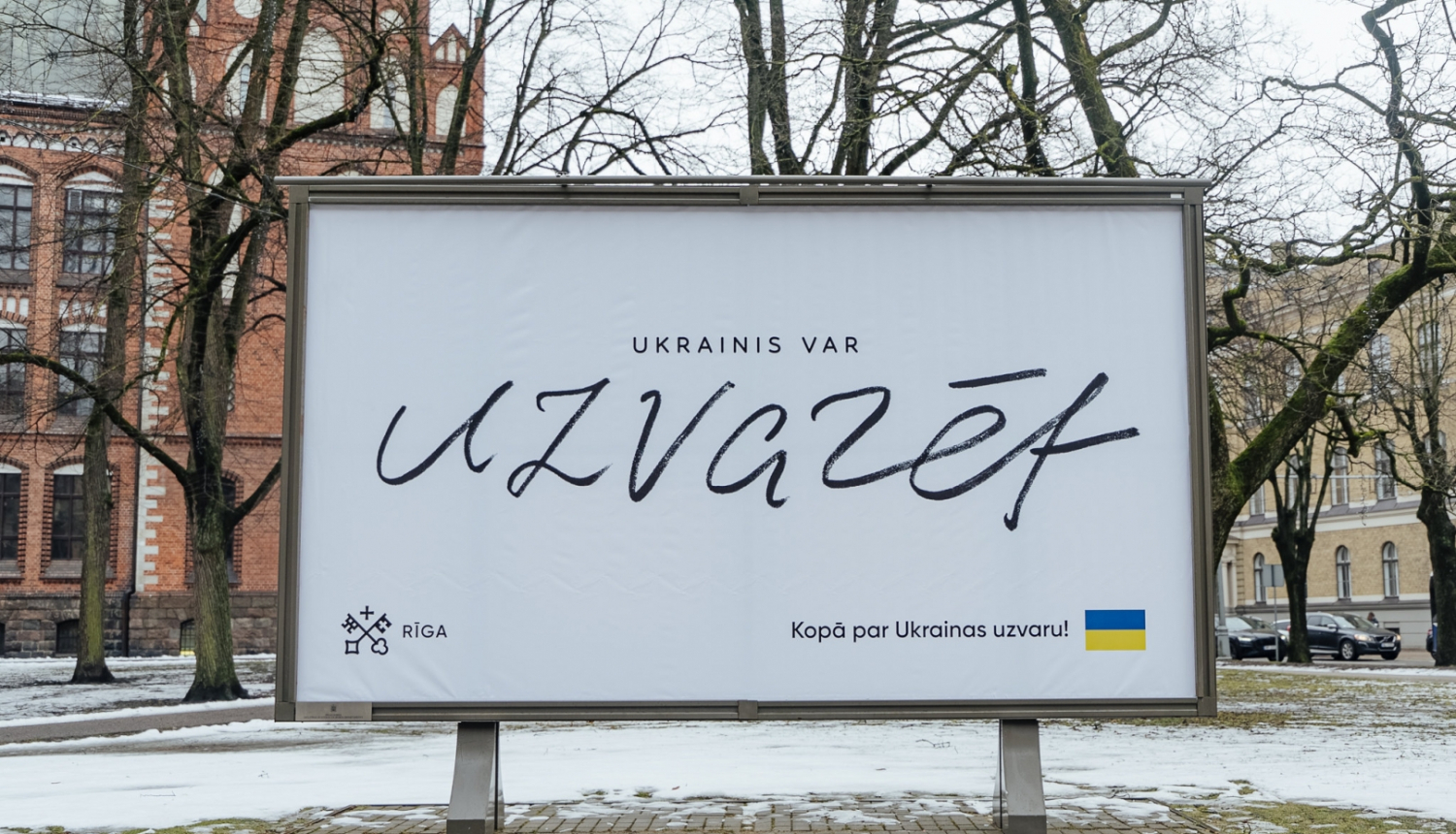 Ukrainas atbalsta plakāts pilsētvidē ar uzralstu "Ukrainis var uzvarēt"