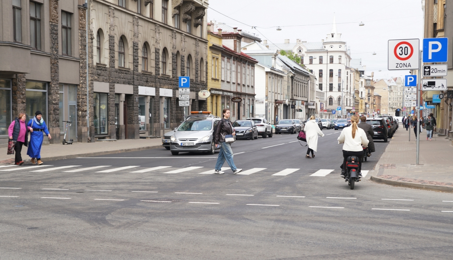 Auto brauc un cilvēki iet pa Matīsa ielu