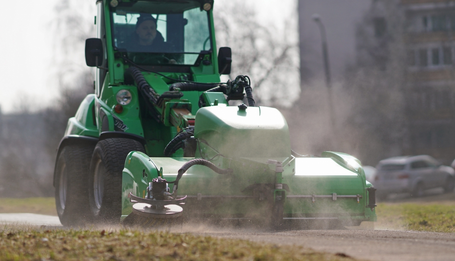 Traktors savāc smiltis no ielas