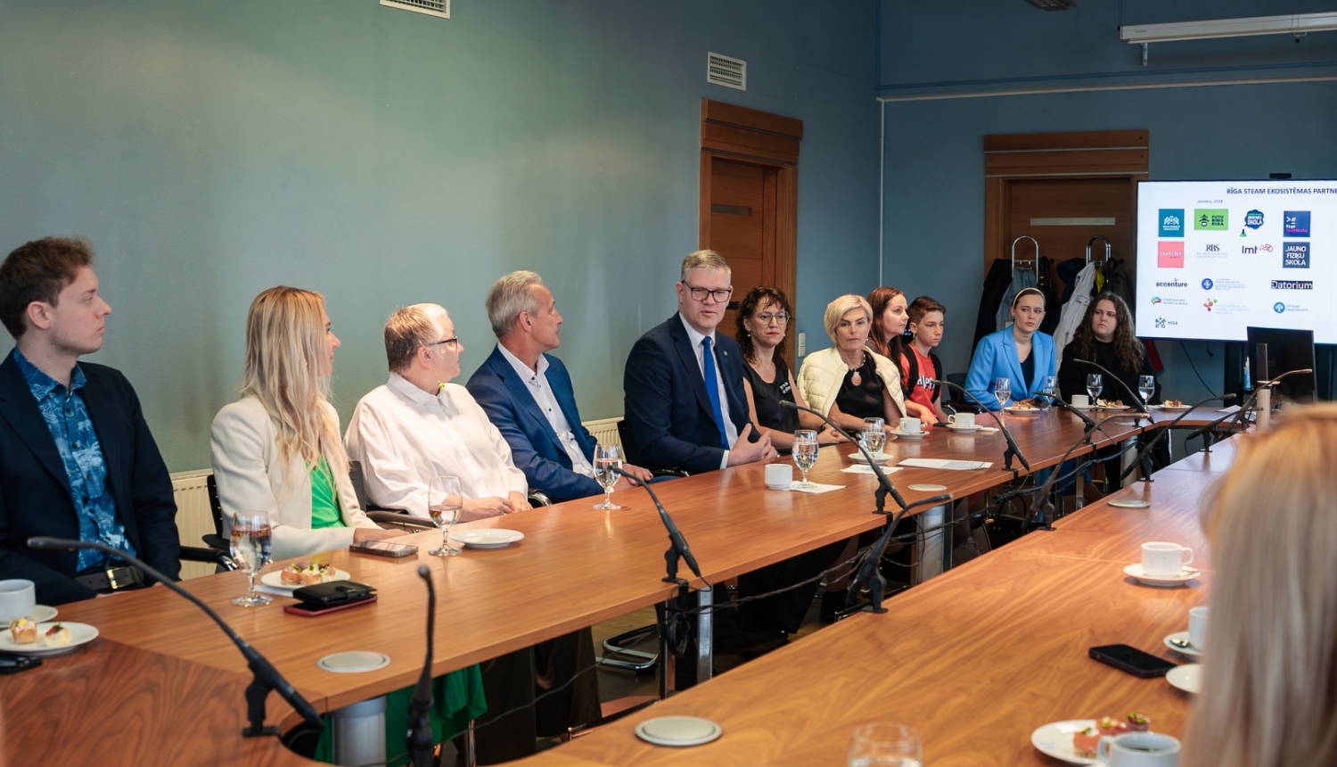 Cilvēki sēž pie galda un skatās prezentāciju